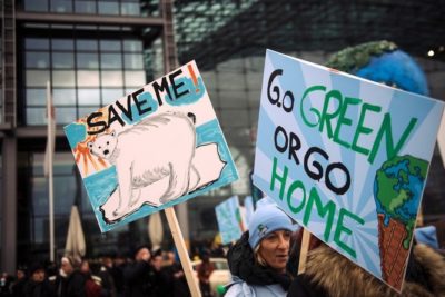 Demonstranten halten am 29.11.2015 auf dem "Global Climate March" in Berlin anlässlich der UN-Klimakonferenz in Paris Schilder mit der Aufschrift "Save Me!" und "Go Green or go Home" hoch. Foto: Gregor Fischer/dpa +++(c) dpa - Bildfunk+++